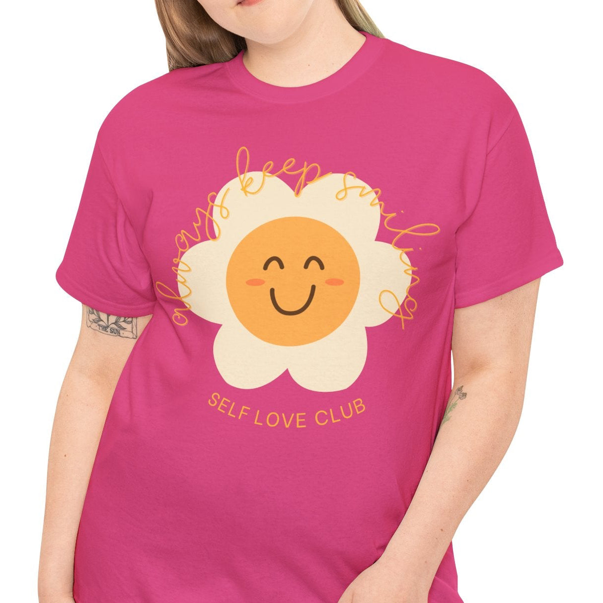 Person wearing a pink t-shirt with a flower graphic and text on a white background