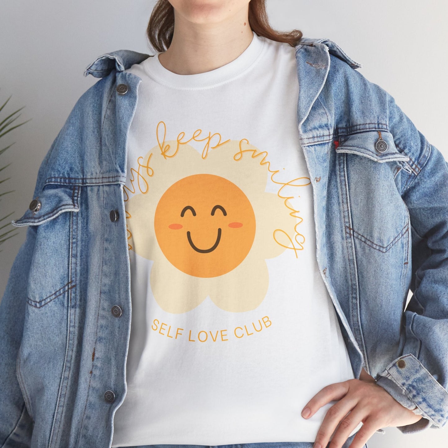 Person wearing a white t-shirt with a flower graphic and text, paired with a denim jacket.