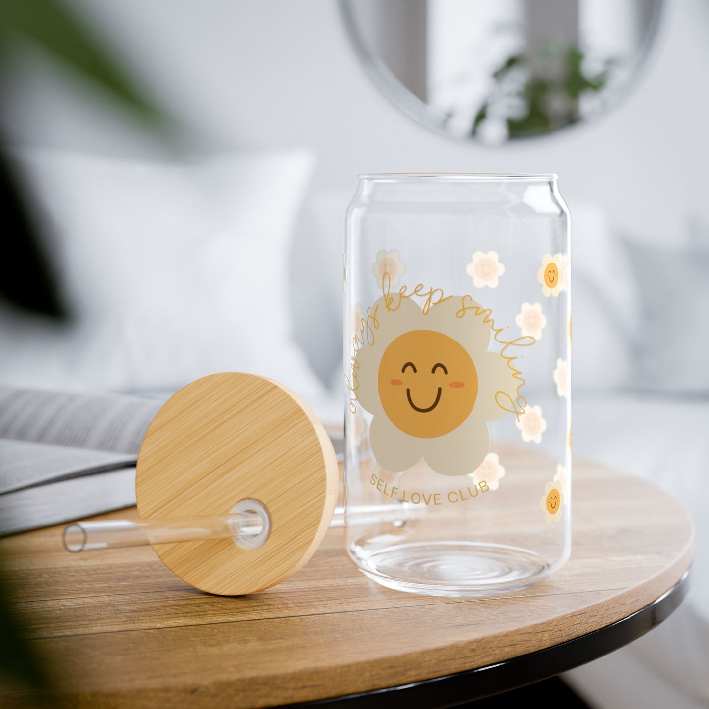 Clear glass tumbler with a happy flower design and wooden lid on a table