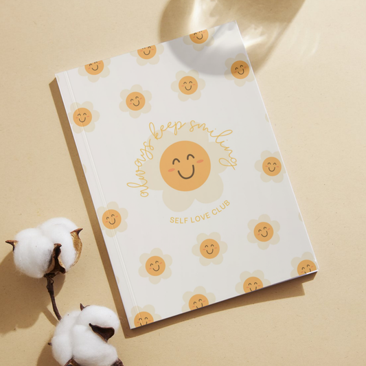Notebook with happy flower face design and text on a beige background
