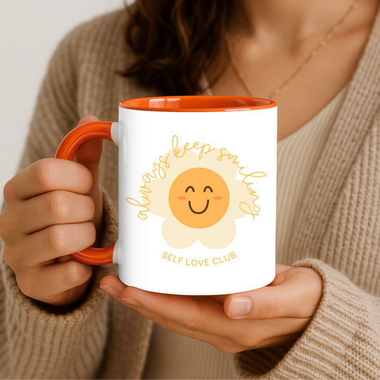 Person holding a mug with a sunflower design and text, wearing a beige sweater.