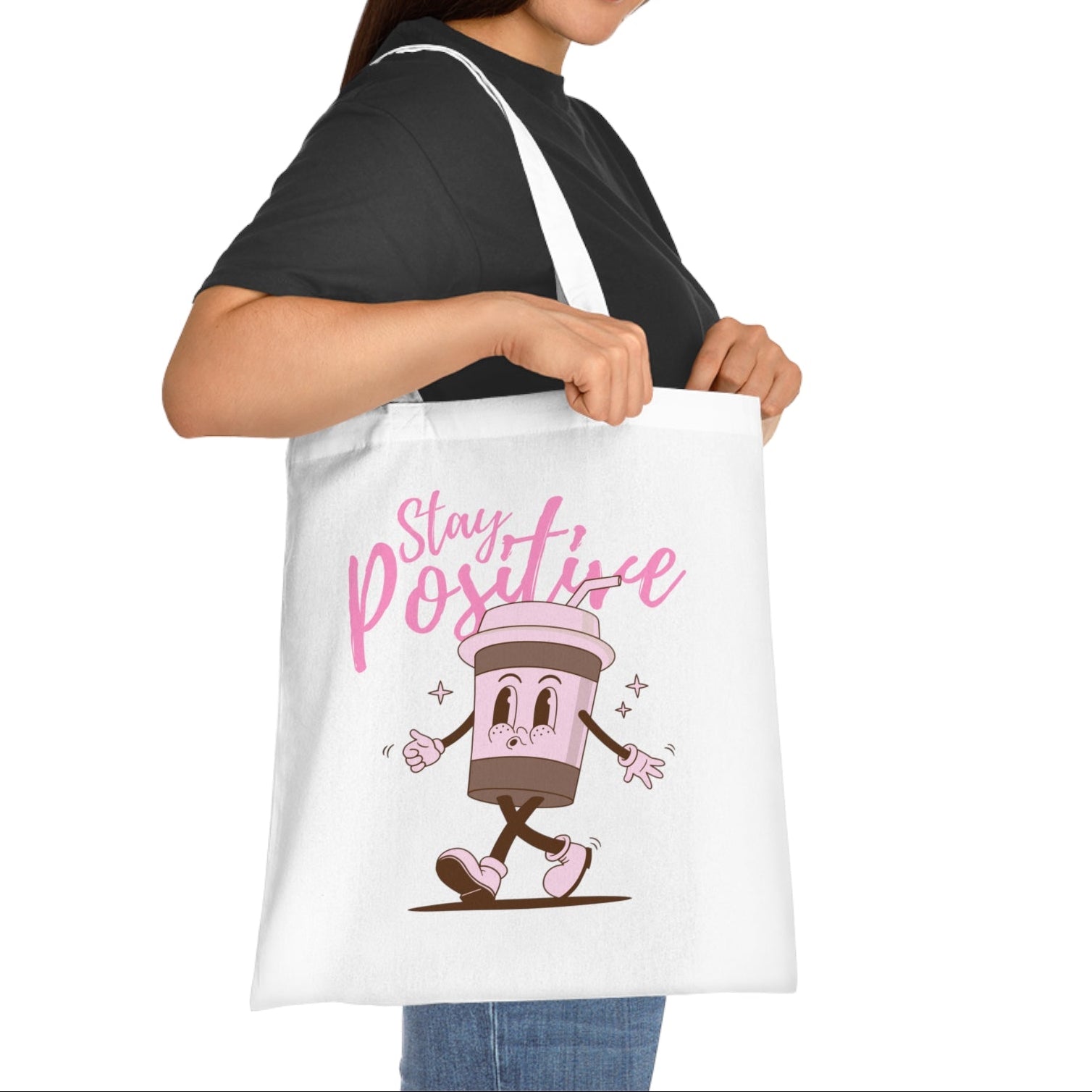 Woman holding a tote bag with a cartoon character and 'Stay Positive' text on a white background