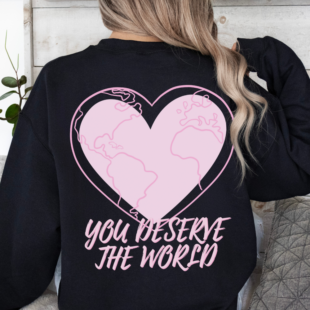Black sweatshirt with pink heart and world map design on the back, worn by a person.
